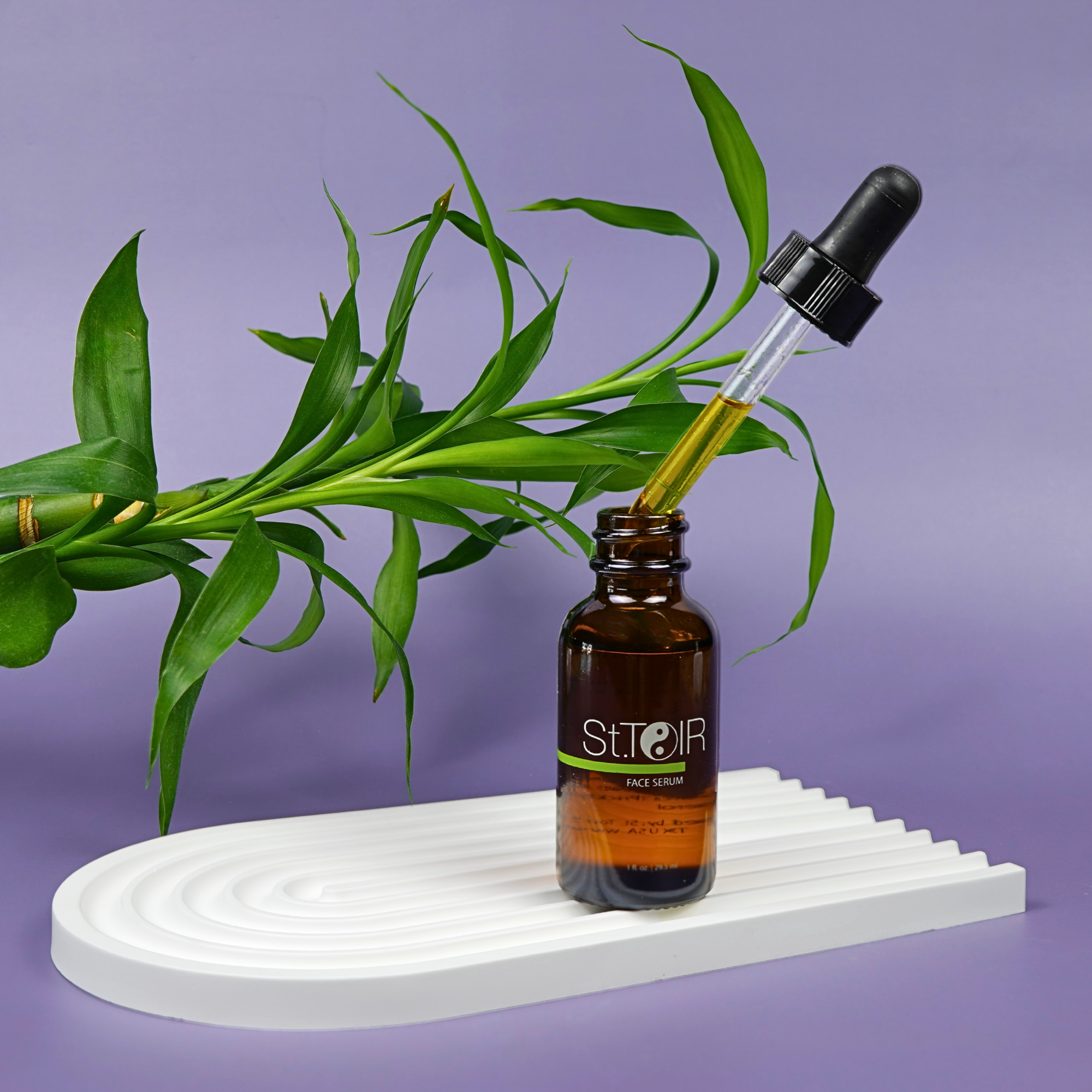 Brown glass bottle with dropper labeled 'STeoir' on a white stand with green leaves against a purple background