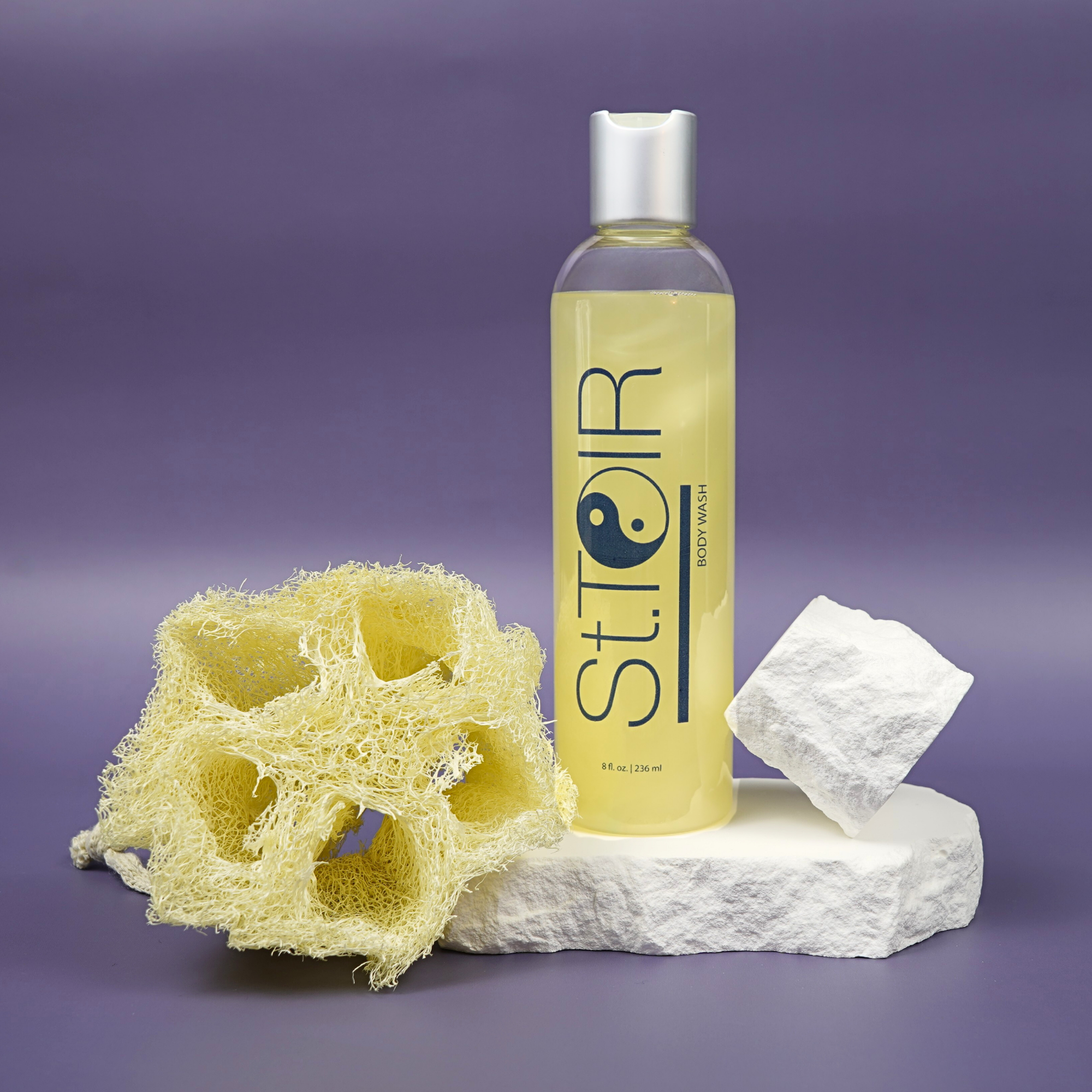 Bottle of St. Toir body wash with a loofah and soap on a purple background