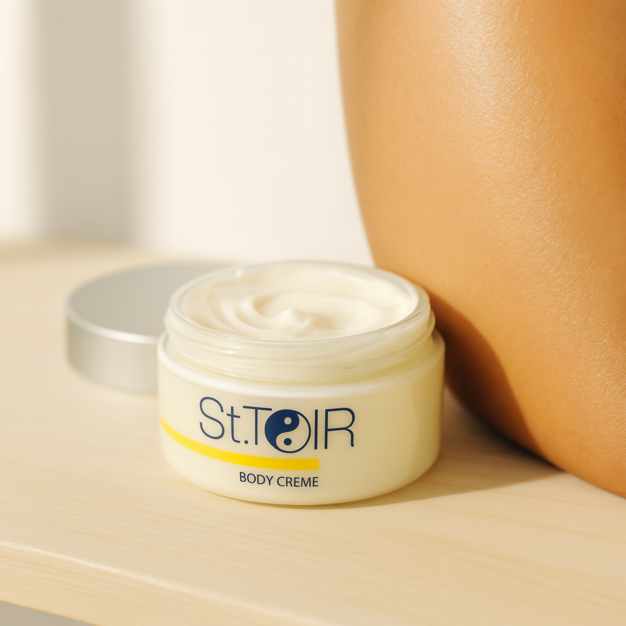 Jar of St. Toir Body Crème with a person's arm in the background
